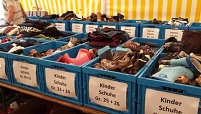 Kisten mit Schuhspenden in Spielfeld in einem Zelt